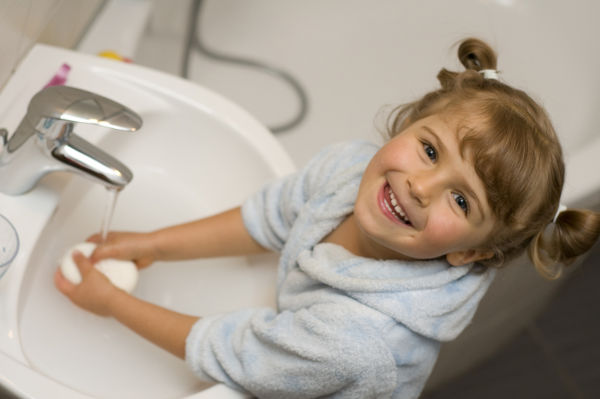 Little girl washing hands in bathroom